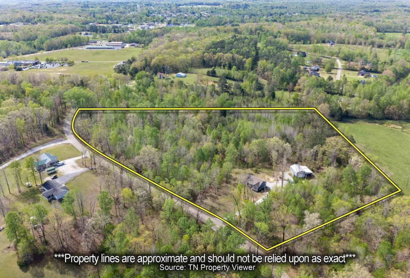 Aerial overview of property's location featuring property boundaries highlighted and a forest
