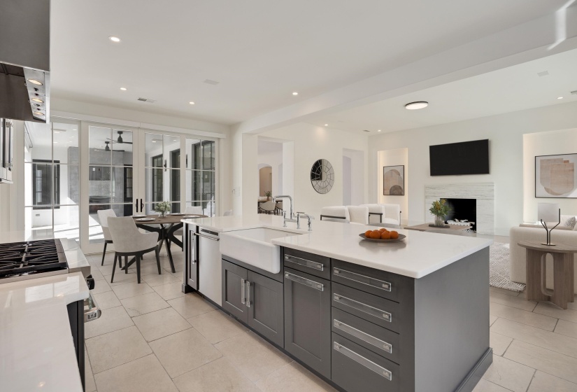 Kitchen with open floor plan, an island with sink, stainless steel appliances, light stone countertops, and recessed lighting