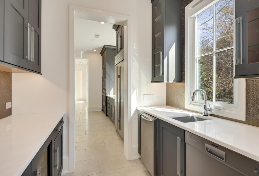 Kitchen featuring stainless steel appliances, glass fronted cabinets, light stone countertops, and light tile patterned floors