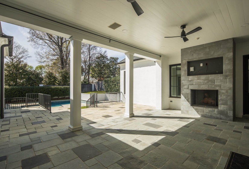 View of patio with a large fireplace and ceiling fan