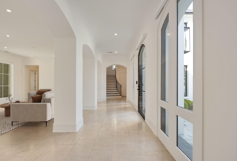 Corridor featuring arched walkways, recessed lighting, and light tile patterned floors