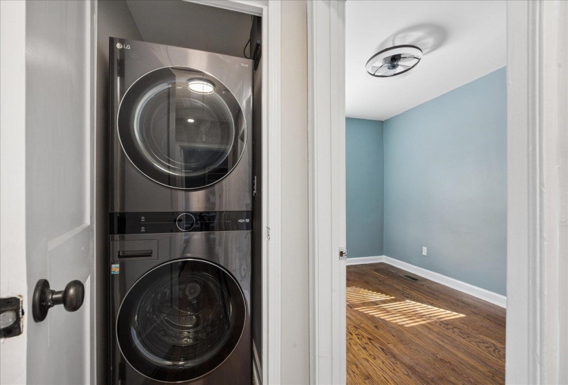 Laundry area featuring stacked washer and dryer and dark wood finished floors