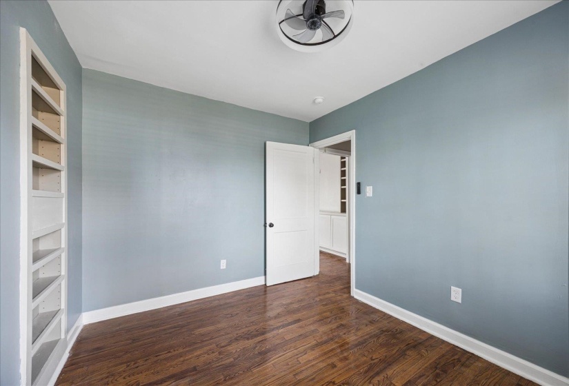 Empty room featuring built in shelves and dark wood-style floors