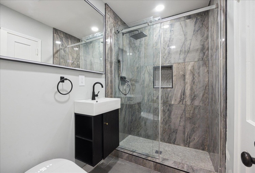 Full bathroom featuring vanity and a marble finish shower