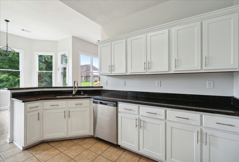 Kitchen with pendant lighting, white cabinets, sink, dishwasher, and light tile patterned floors