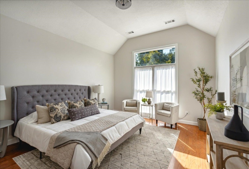Bedroom featuring hardwood / wood-style floors, vaulted ceiling, and a textured ceiling
