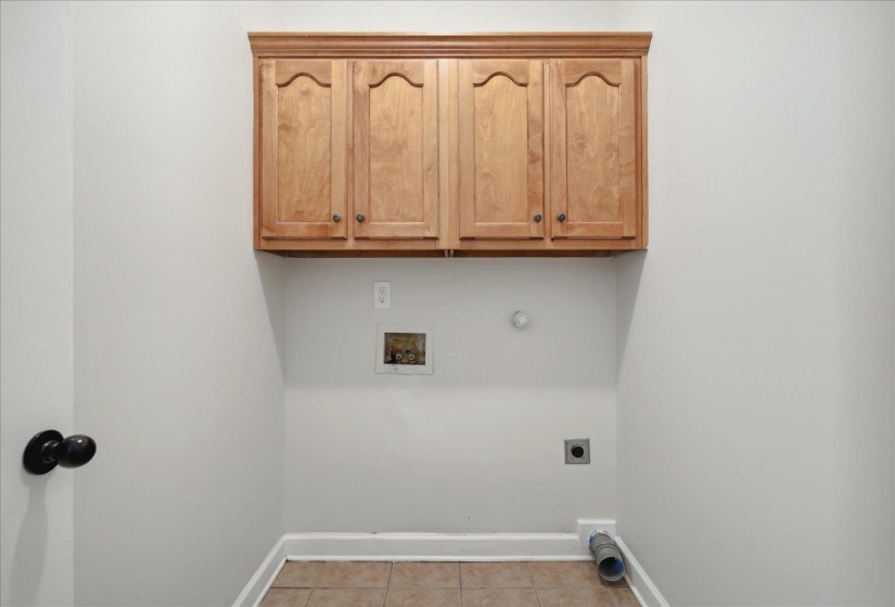 Clothes washing area with light tile patterned floors, gas dryer hookup, washer hookup, cabinets, and electric dryer hookup