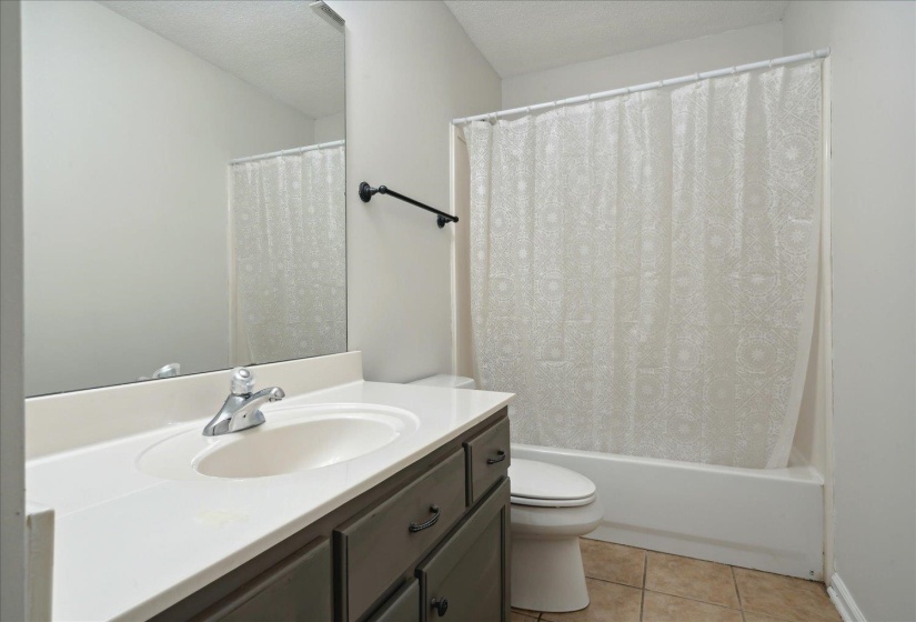 Full bathroom with shower / bathtub combination with curtain, a textured ceiling, toilet, tile patterned floors, and vanity
