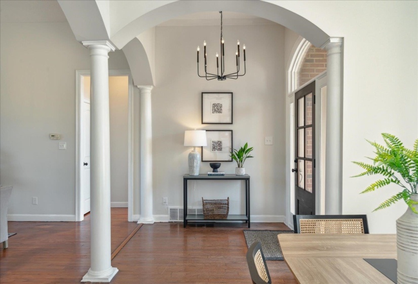 Entryway with ornate columns, a notable chandelier, and dark hardwood / wood-style flooring