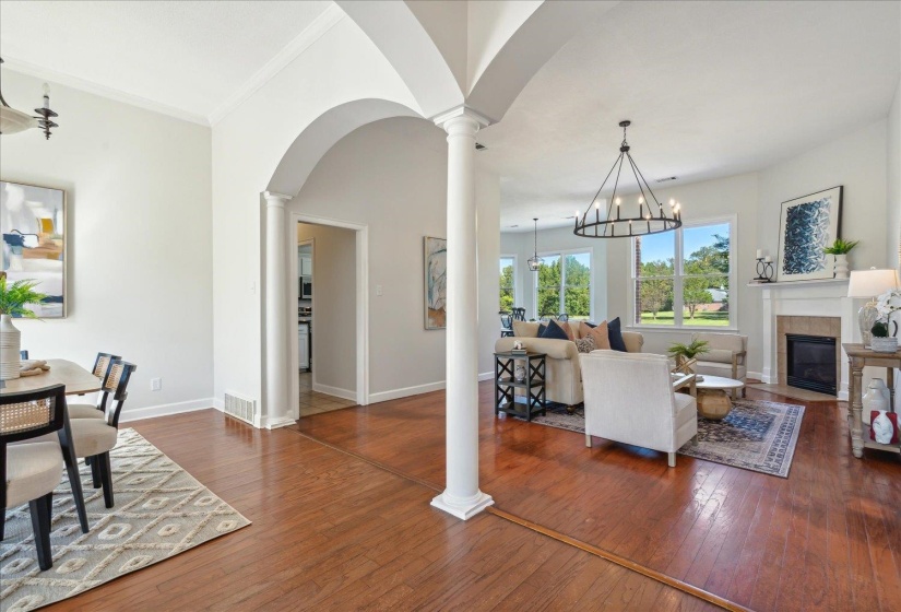 Living room with ornamental molding, a fireplace, dark wood-type flooring, and a chandelier