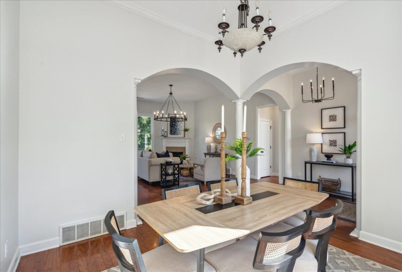 Dining space with dark hardwood / wood-style floors, crown molding, and decorative columns