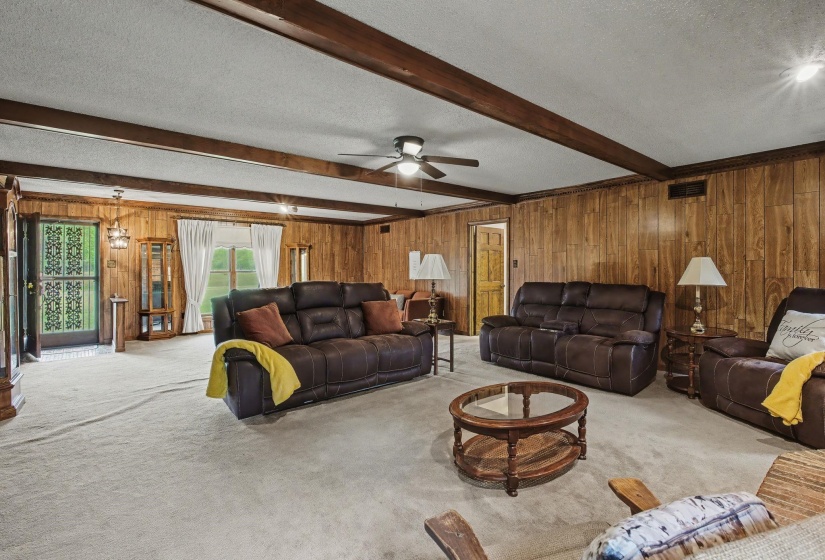 Living area featuring a textured ceiling, carpet floors, wooden walls, and ceiling fan