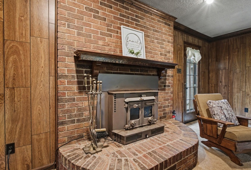 Sitting room with wooden walls, a textured ceiling, a fireplace, carpet floors, and crown molding