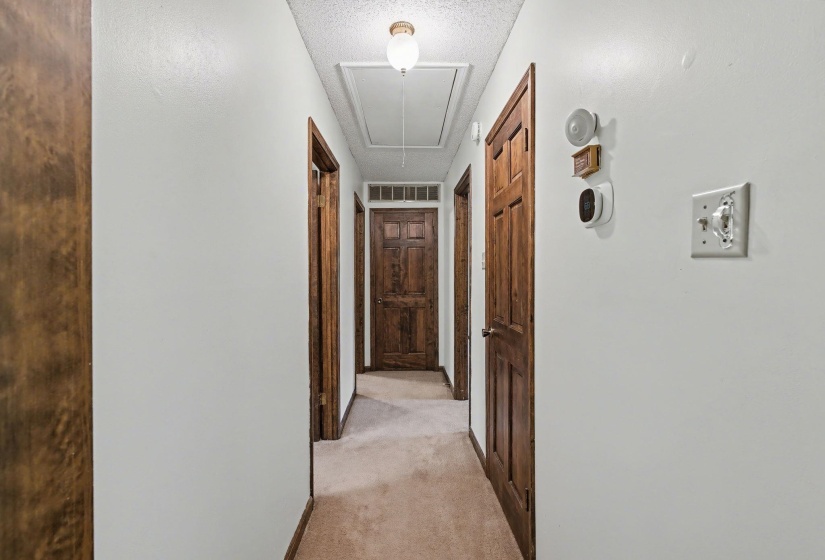 Hallway featuring light colored carpet and a textured ceiling