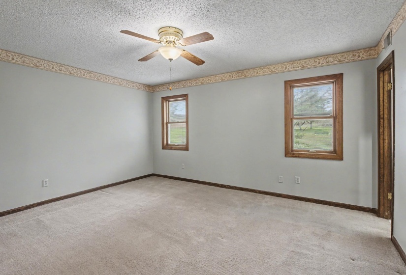 Spare room featuring light colored carpet, ceiling fan, and a textured ceiling