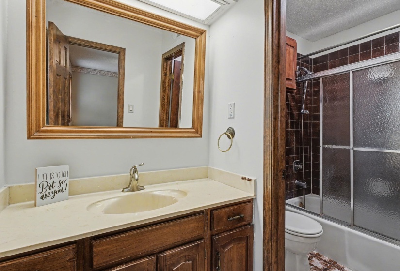 Bathroom featuring vanity, enclosed tub / shower combo, and a textured ceiling