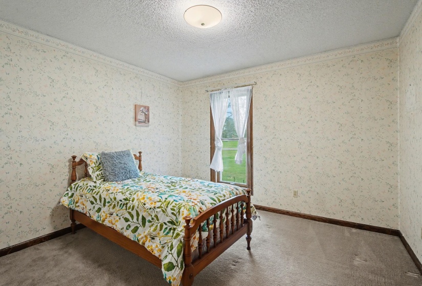 Bedroom featuring carpet flooring, a textured ceiling, and wallpapered walls