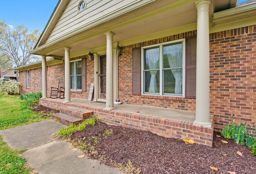 Doorway to property with a porch and brick siding