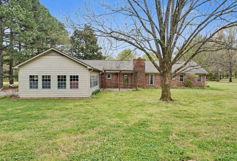 Rear view of property with a patio, a lawn, a chimney, and brick siding