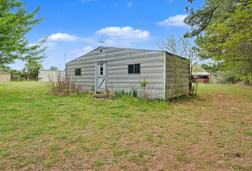 Back of house featuring a lawn and an outbuilding