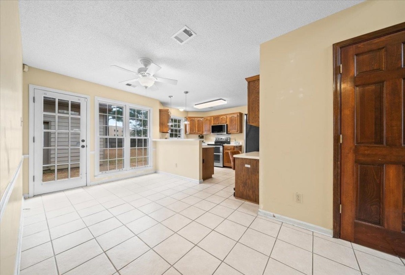 Kitchen featuring a textured ceiling, light countertops, stainless steel appliances, light tile patterned floors, and brown cabinets