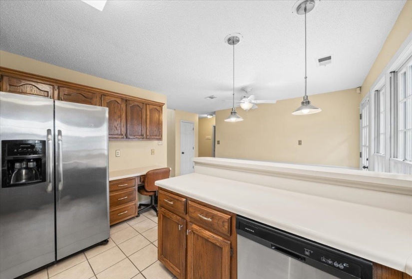 Kitchen featuring appliances with stainless steel finishes, a textured ceiling, light countertops, light tile patterned flooring, and decorative light fixtures