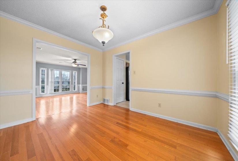 Spare room featuring crown molding, light wood-style floors, a textured ceiling, and a ceiling fan