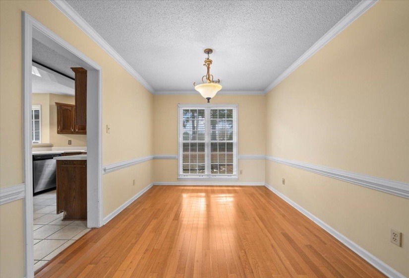 Unfurnished dining area featuring crown molding, a textured ceiling, and light wood-style floors