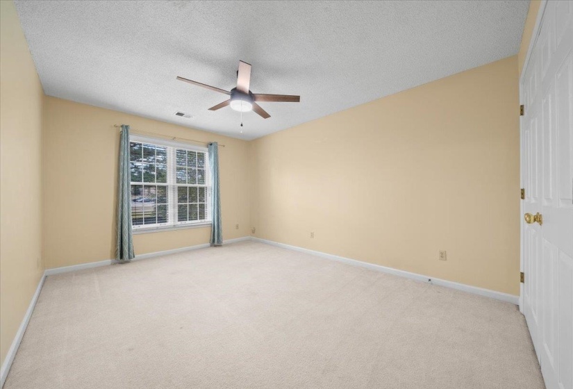 Spare room featuring light colored carpet, a textured ceiling, and a ceiling fan