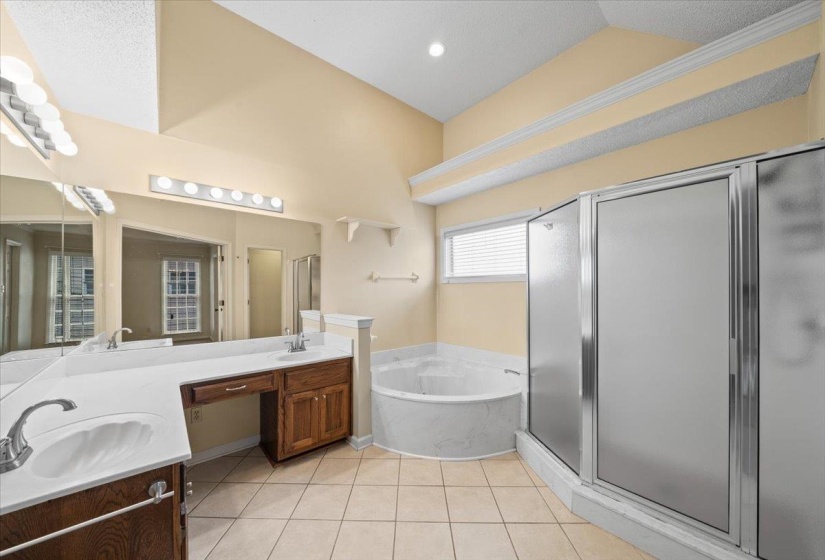 Full bathroom featuring a bath, a shower stall, double vanity, and light tile patterned flooring
