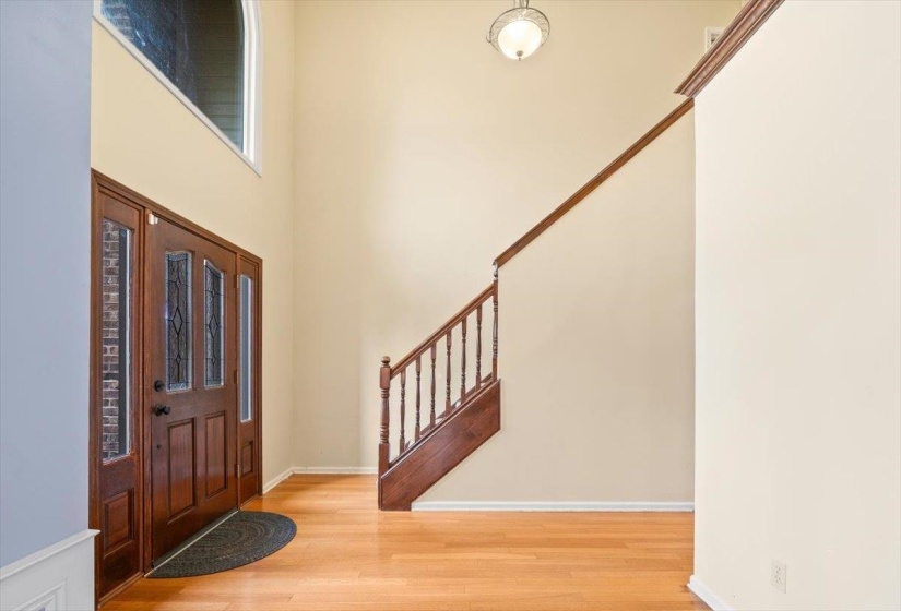 Entryway featuring light wood-type flooring, stairs, and a high ceiling