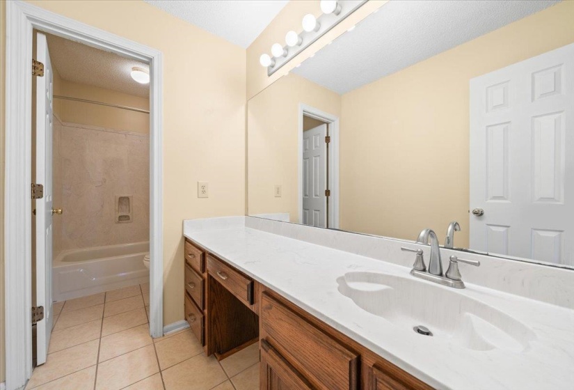 Bathroom with vanity, a textured ceiling, light tile patterned floors, and bathing tub / shower combination