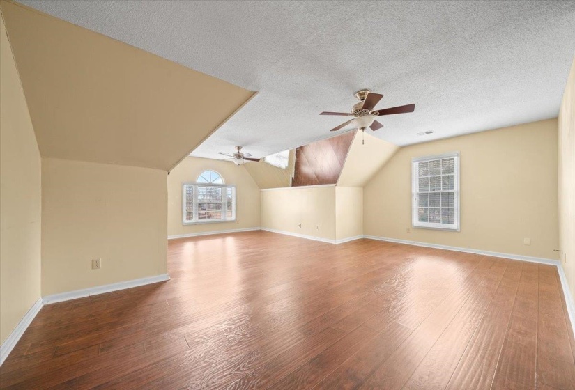 Additional living space featuring vaulted ceiling, a textured ceiling, ceiling fan, and wood finished floors