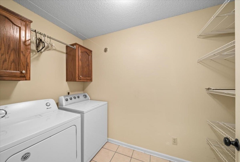 Washroom with light tile patterned floors, washer and dryer, a textured ceiling, and cabinet space
