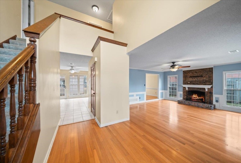 Unfurnished living room featuring a textured ceiling, light wood finished floors, a brick fireplace, and ceiling fan