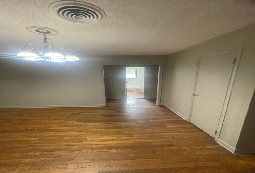 Hall with a textured ceiling, wood finished floors, and suspended lighting