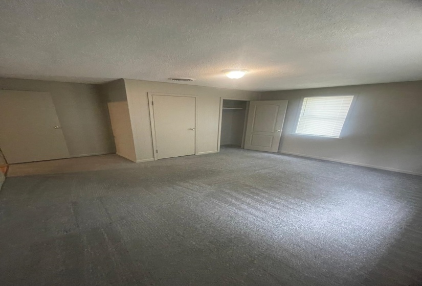 Unfurnished bedroom featuring a textured ceiling, carpet flooring, and a closet