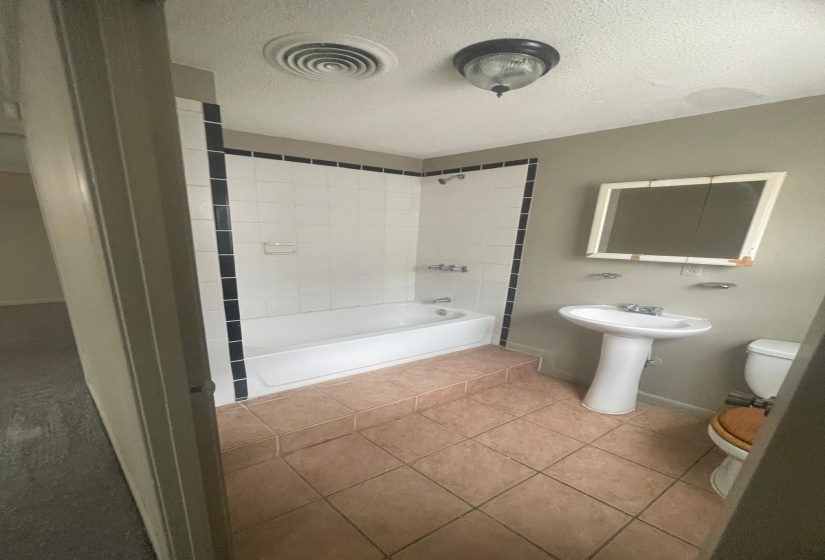 Bathroom featuring tile patterned flooring, a textured ceiling, and  shower combination