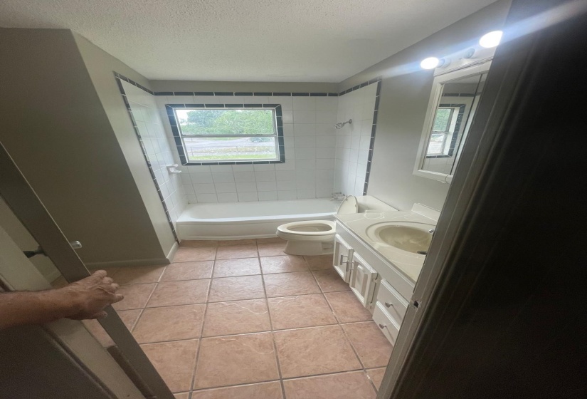 Bathroom with vanity, shower / bathtub combination, light tile patterned floors, and a textured ceiling