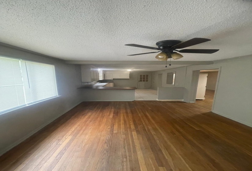 Unfurnished living room featuring light wood finished floors, a textured ceiling, and ceiling fan