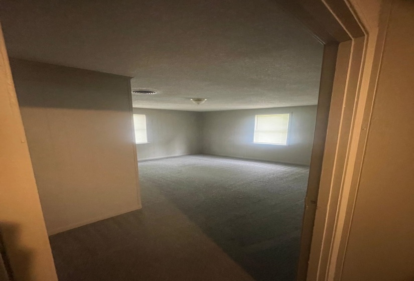 Empty room featuring plenty of natural light and dark carpet