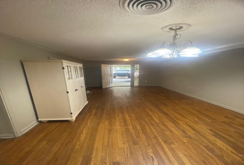 Unfurnished living room featuring a textured ceiling, dark wood-style flooring, and hanging lights