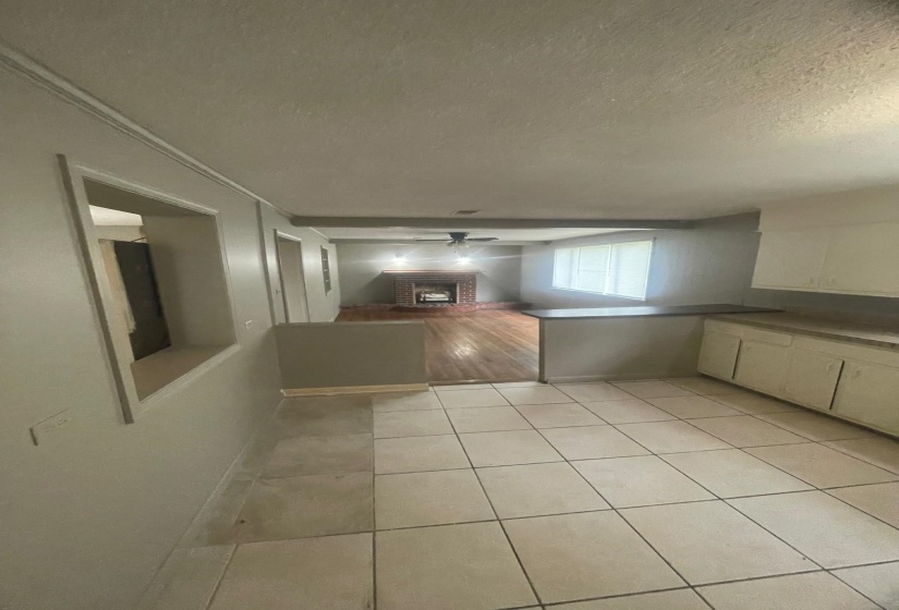 Unfurnished dining area with a textured ceiling, a fireplace, ceiling fan, and light tile patterned flooring