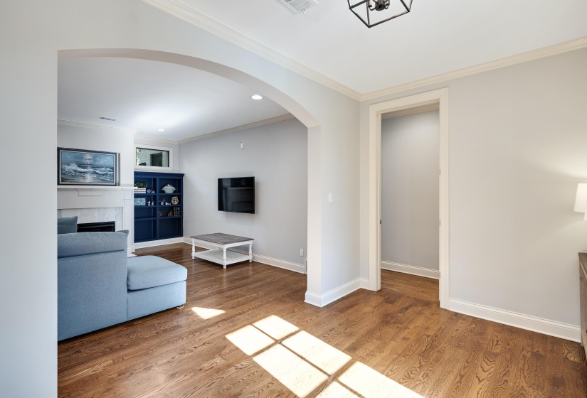 Living room featuring arched walkways, crown molding, light wood-style flooring, a fireplace, and recessed lighting