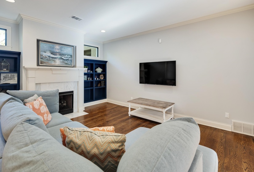 Living area featuring ornamental molding, dark wood-style flooring, a premium fireplace, recessed lighting, and built in features