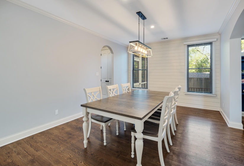 Dining space featuring arched walkways, crown molding, dark wood finished floors, wooden walls, and recessed lighting