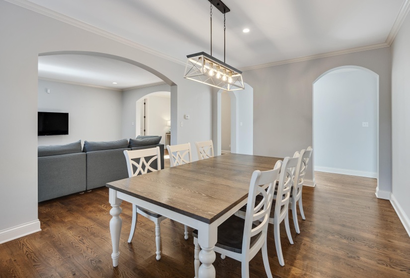 Dining space with crown molding, dark wood-style flooring, and recessed lighting