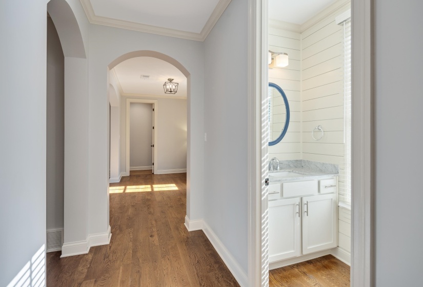 Hall featuring arched walkways, ornamental molding, and light wood finished floors