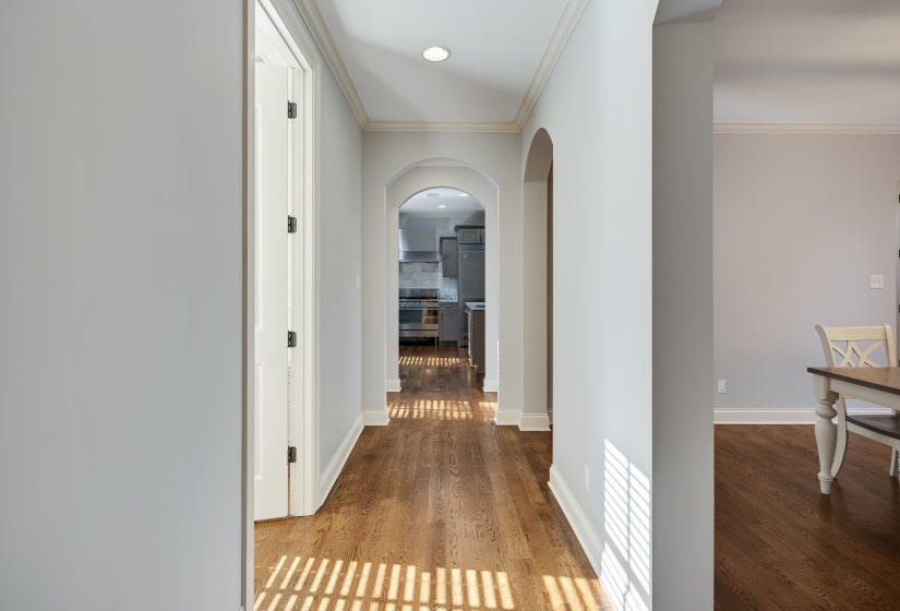 Hall featuring crown molding, arched walkways, and wood finished floors