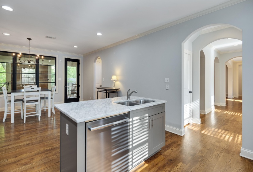 Kitchen featuring gray cabinetry, stainless steel dishwasher, crown molding, an island with sink, and dark wood finished floors